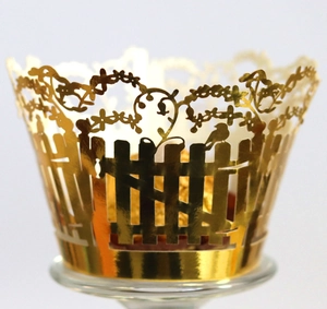 Macro detail of gold laser-cut cupcake wrappers with bird and fence pattern