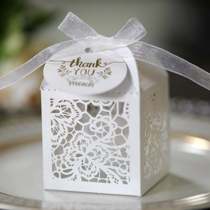 Detail of white lace laser-cut wedding favor box with ribbon and thank you tag