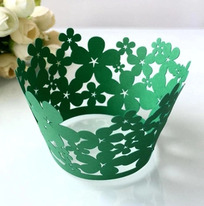 Detail of laser-cut green cupcake wrapper with intricate floral and star hollow patterns