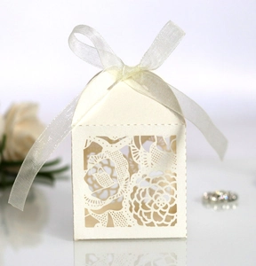 Détail de la boîte cadeau ajourée rose en papier blanc crème avec un ruban de soie