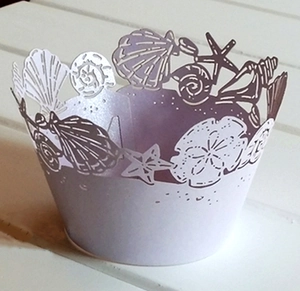 Close-up of laser-cut cupcake wrappers with ocean shell patterns in pearlescent purple