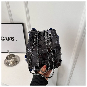 Détail d'un sac seau chic en paillettes noires avec une bandoulière chaîne argentée