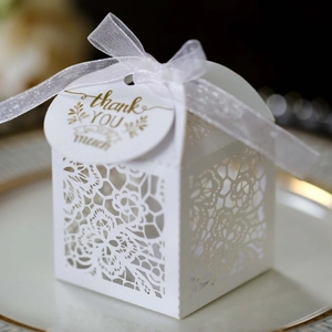 Detailed laser-cut white favor box with elegant rose lace patterns and a white satin bow