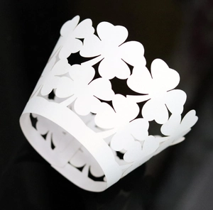 Detailed laser-cut white cupcake wrapper featuring intricate clover hollow patterns