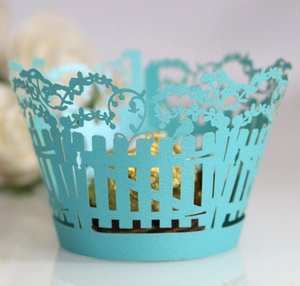 Detail of light blue laser-cut cupcake wrappers with floral garden and bird patterns