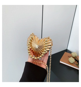 Detail of heart-shaped metal bag with radial pleats and elegant pearl strap