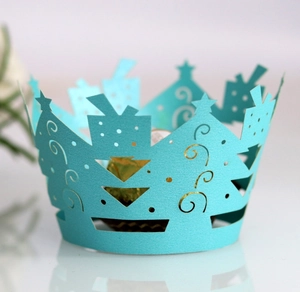 Detail of blue laser-cut Christmas cupcake wrapper with holiday tree and gift box patterns