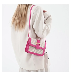 Detail of contrast straw crossbody bag with pink leather trim and gold buckle on a model