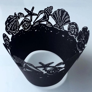 Detailed laser-cut black cupcake wrapper with hollow starfish and seashell patterns