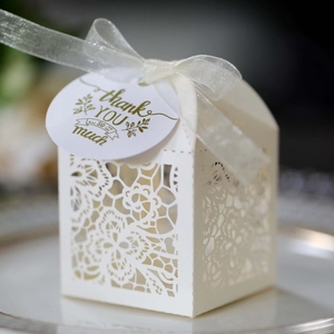 Detail of white laser-cut wedding favor box with floral patterns and thank you tag