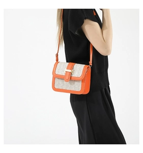 Chic straw woven crossbody bag with bright orange leather trim and gold buckle detail