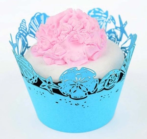 Close-up of light blue laser cut cupcake wrapper with starfish and shell patterns