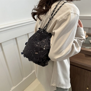 Sac seau noir à paillettes tendance avec bandoulière chaîne porté par un mannequin élégant
