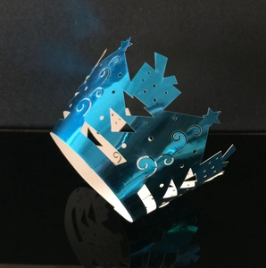 Close-up of laser-cut blue metallic crown cupcake wrapper with hollow star pattern