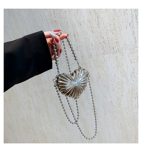 Detail of silver heart-shaped handbag featuring radial texture and pearl chain handle