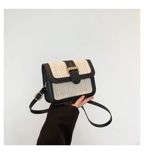 Detail of straw woven crossbody bag featuring black leather trim and magnetic closure