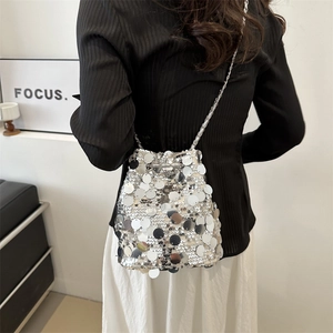 Sac seau chic à paillettes argentées avec chaîne en métal porté par un mannequin