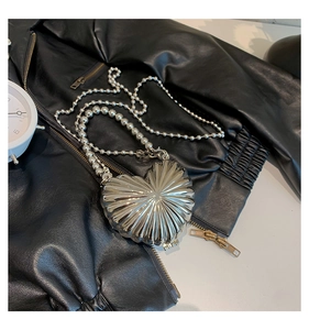 Detail of silver heart-shaped bag with radial pleated texture on black leather