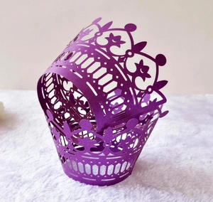 Detail of purple laser-cut crown cupcake wrappers with intricate hollow patterns