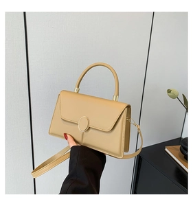 Close-up of khaki leather handbag with gold oval metal lock and elegant top handle