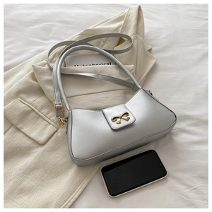 Close-up of silver-grey underarm bag featuring a metallic bow buckle and leather texture