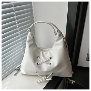 Close-up of white leather hobo bag featuring criss-cross lace-up design and silver eyelets