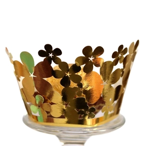 Golden laser-cut flower cupcake wrappers on glass stand for wedding party decoration