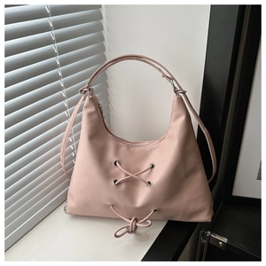 Detail of dusty pink leather tote featuring decorative eyelets and stylish lace-up design