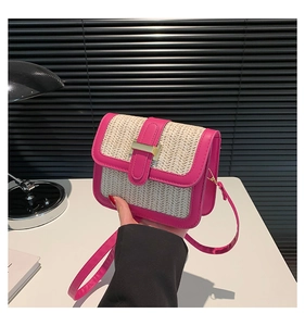 Detail of contrast stitch straw weave crossbody bag with vibrant pink leather trim