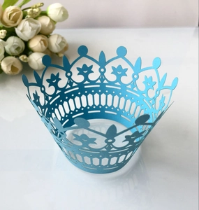 Detail of light blue crown laser-cut cupcake wrappers on a white reflective surface