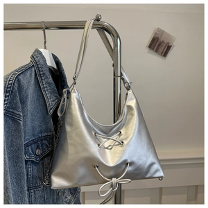 Close-up of shiny silver metallic bag with lace-up detail and metal chain on a hanger