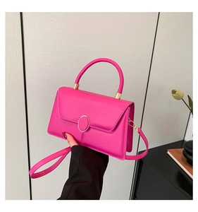 Detail of fuchsia handbag with gold clasp, showing hand-held style and leather texture
