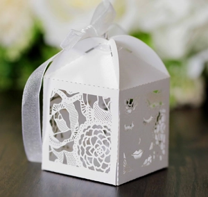 Détail de la boîte à dragées blanche ajourée au laser avec motifs roses et ruban satin