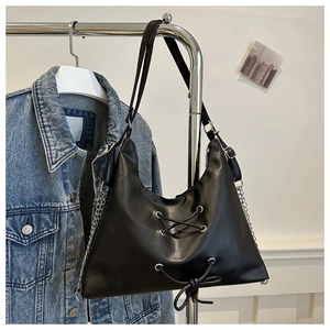 Detail of black leather hobo bag with lace-up design and silver chain strap hanging