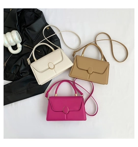 Flat lay of small rectangular crossbody bags in cream, tan, and magenta with gold buckles