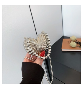 Detail of silver heart-shaped crossbody bag with pleated texture and beaded handle