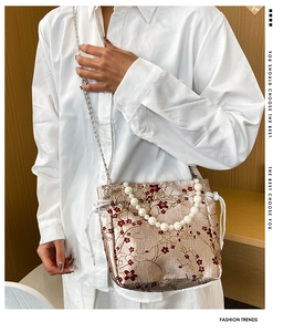 Detail of floral embroidery and pearl handle on large jacquard shoulder bucket bag