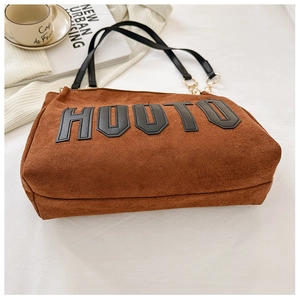 Macro shot of brown suede tote bag featuring black HOOTU leather letters and gold hardware