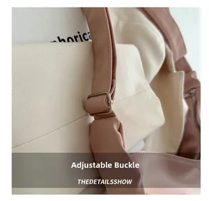 Detail of adjustable metal buckle and wide pink shoulder strap on a casual dumpling bag
