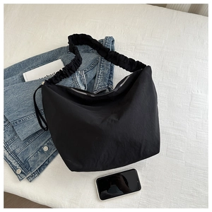 Detail of black pleated shoulder strap and nylon fabric on large tote bag