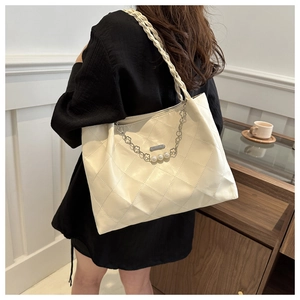 Detail of cream white tote bag with quilted texture, pearl charms and braided handle