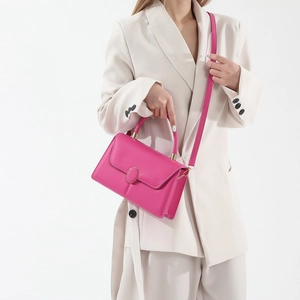 Vibrant magenta crossbody bag with metal buckle shown with a chic white blazer suit