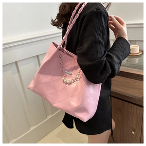 Detail of pink quilted tote bag with braided handle and decorative pearl metal chain