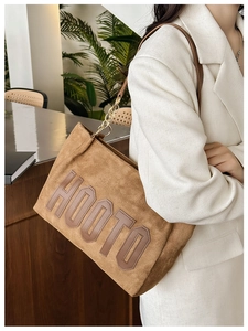 Detail of khaki corduroy tote bag showing metal chain strap and embroidered HOOTO letters