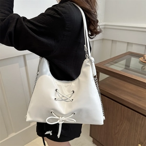 White minimalist crescent shoulder bag with lace-up bow and metal chain strap detail