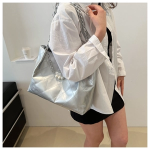Detail of silver quilted tote bag with metallic finish, pearl charm and chain strap