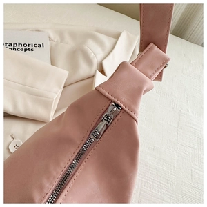 Detail of pink PU leather crossbody bag with silver zipper and knot strap detail