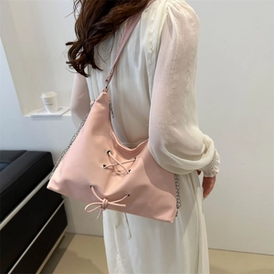 Pink minimalist shoulder bag with ribbon bow and silver chain detail on model