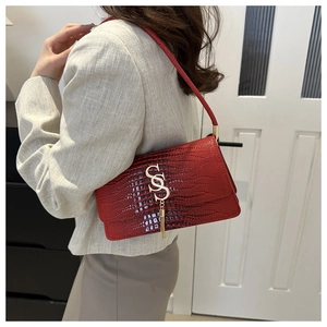 Detail of red croc-embossed shoulder bag with gold logo and long tassel decoration