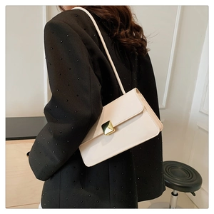 Piccola borsa quadrata crema chic con fibbia dorata indossata sulla spalla su blazer nero